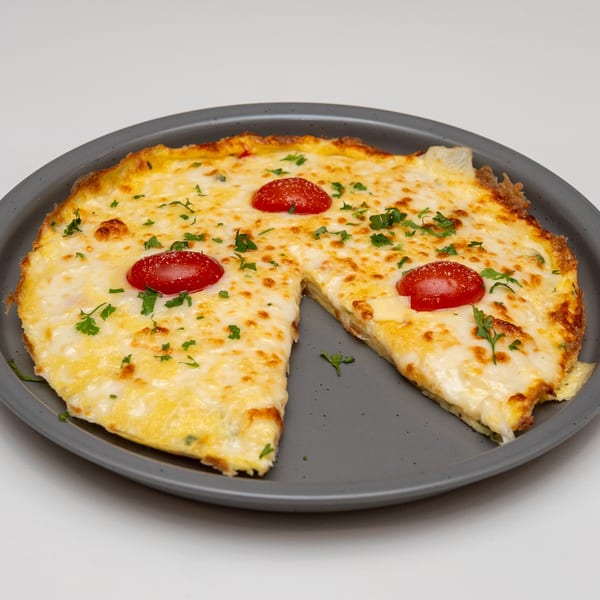 Cheesy baked dish topped with tomato slices and parsley, cut into pieces on a gray plate.